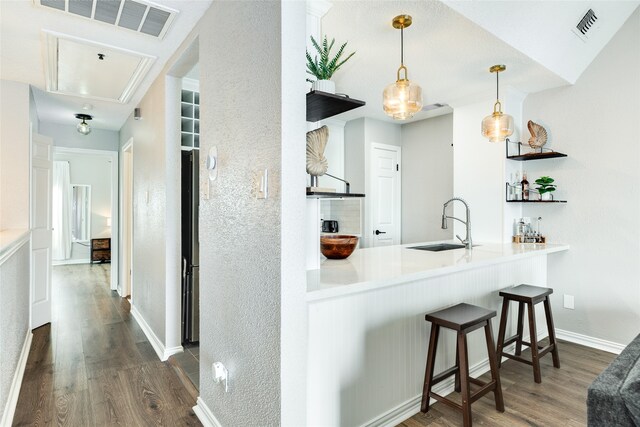 kitchen featuring kitchen peninsula, dark hardwood / wood-style floors, hanging light fixtures, and sink