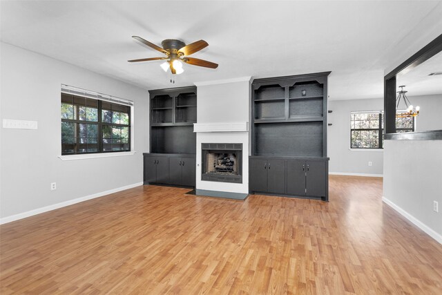 unfurnished living room featuring hardwood / wood-style floors and ceiling fan with notable chandelier