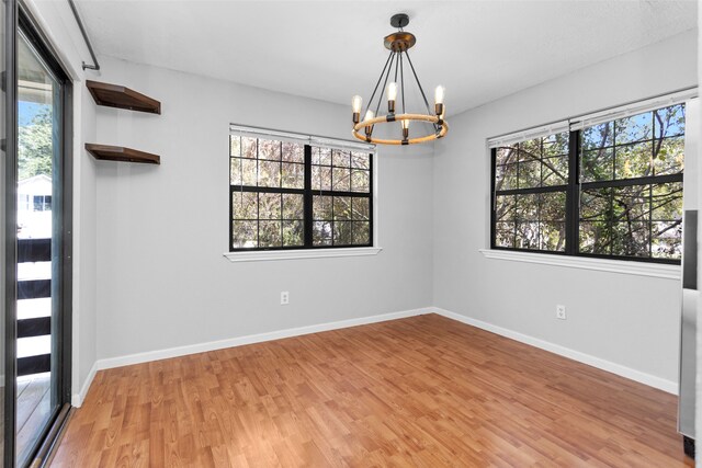 empty room with a notable chandelier and light wood-type flooring