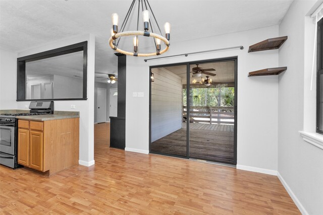 kitchen with pendant lighting, ceiling fan with notable chandelier, gas stove, and light wood-type flooring