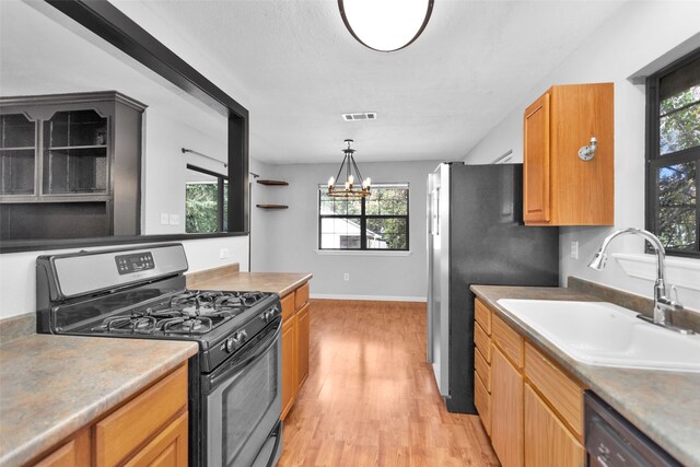 kitchen featuring hanging light fixtures, sink, an inviting chandelier, appliances with stainless steel finishes, and light hardwood / wood-style floors