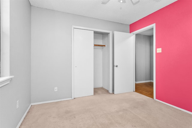 unfurnished bedroom featuring a closet, ceiling fan, a textured ceiling, and light colored carpet