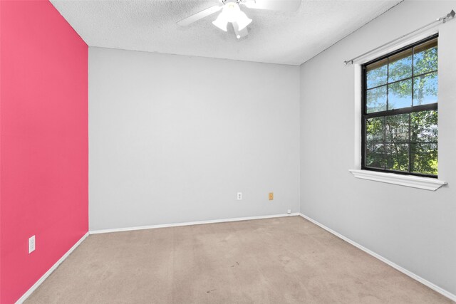 empty room with a textured ceiling, light colored carpet, and ceiling fan