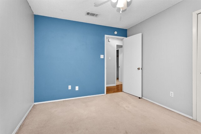 spare room featuring a textured ceiling, light colored carpet, and ceiling fan