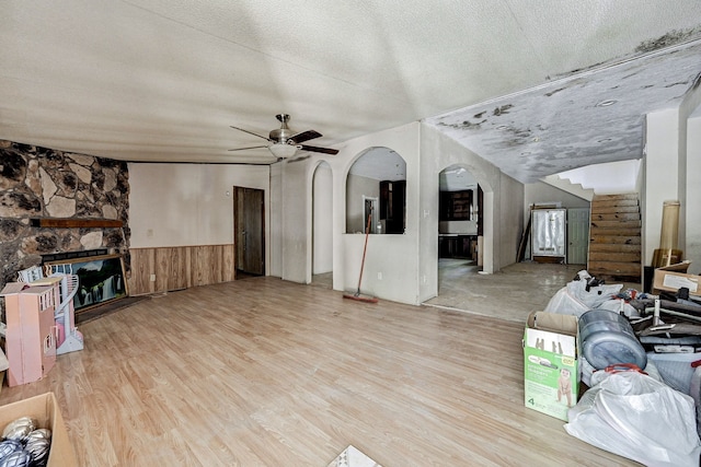 living room featuring light hardwood / wood-style floors, a textured ceiling, a fireplace, and ceiling fan