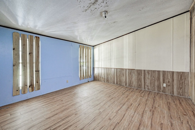 spare room featuring light hardwood / wood-style floors and a textured ceiling