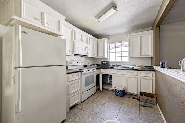 kitchen featuring white appliances, a textured ceiling, white cabinetry, and light tile patterned floors