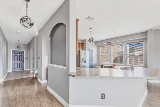 kitchen featuring stainless steel refrigerator with ice dispenser, decorative light fixtures, and light wood-type flooring