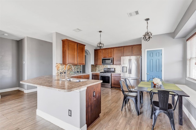 kitchen featuring appliances with stainless steel finishes, light hardwood / wood-style flooring, backsplash, and pendant lighting