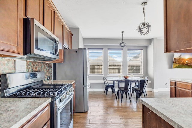 kitchen with light hardwood / wood-style flooring, stainless steel appliances, and decorative light fixtures