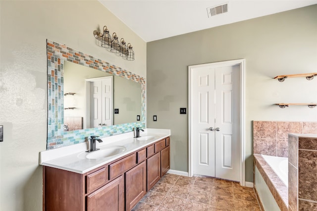 bathroom with vanity, tiled tub, and tile patterned flooring