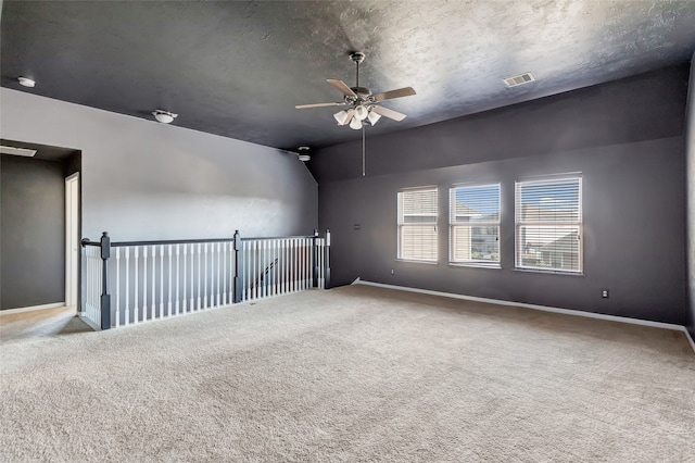 empty room with ceiling fan, lofted ceiling, a textured ceiling, and carpet floors