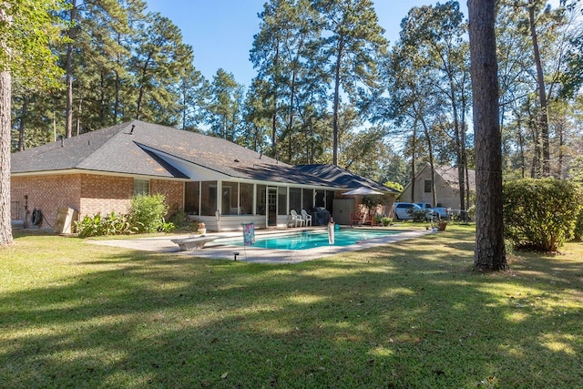 rear view of house featuring a sunroom, a yard, and a patio area