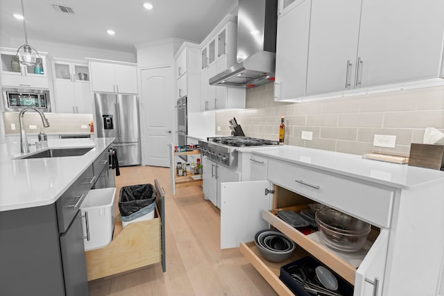 kitchen with wall chimney exhaust hood, appliances with stainless steel finishes, pendant lighting, and white cabinets