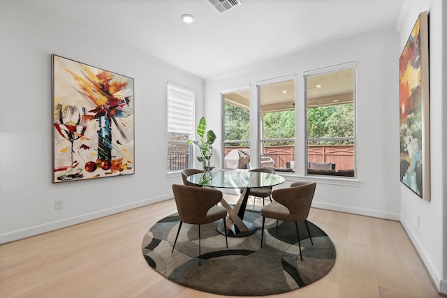 dining room with crown molding and light wood-type flooring