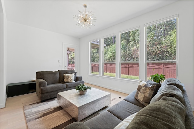 living room with a wealth of natural light, a chandelier, and light hardwood / wood-style floors