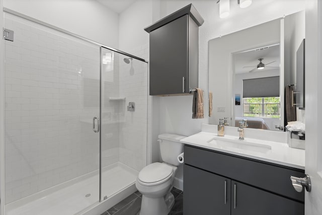 bathroom featuring a shower with door, vanity, toilet, and ceiling fan