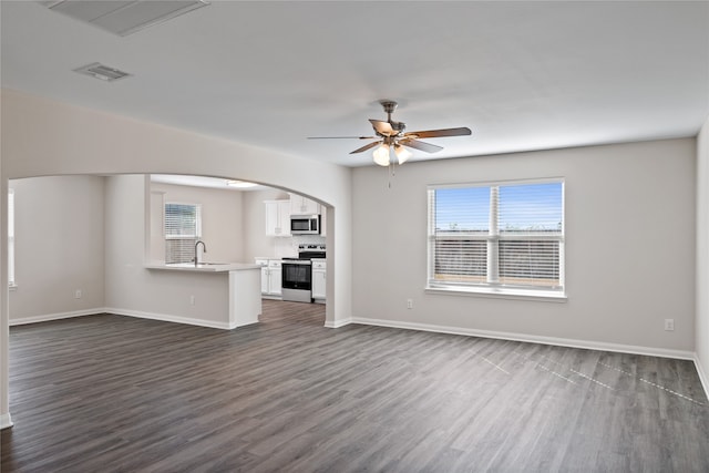 unfurnished living room with dark wood-type flooring, ceiling fan, and sink