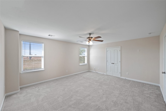 unfurnished room featuring ceiling fan, a healthy amount of sunlight, and light colored carpet