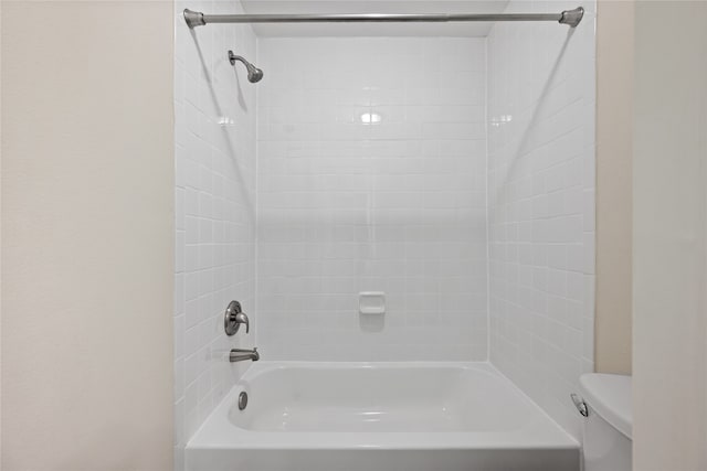 bathroom featuring tiled shower / bath and toilet