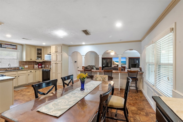 dining room featuring ornamental molding, sink, and ornate columns