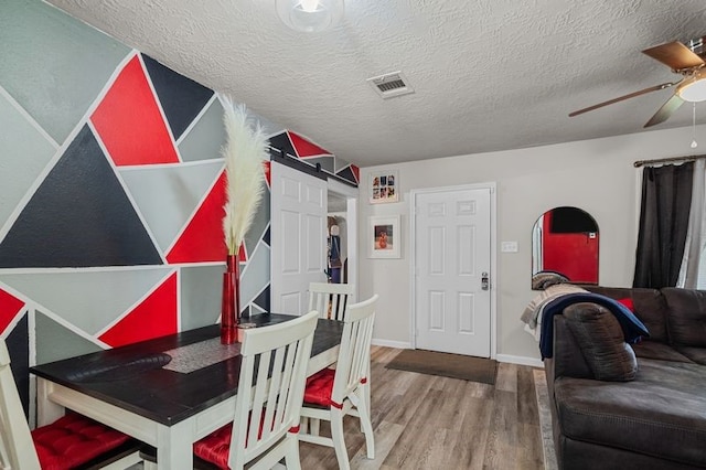 dining room featuring a textured ceiling, wood-type flooring, and ceiling fan