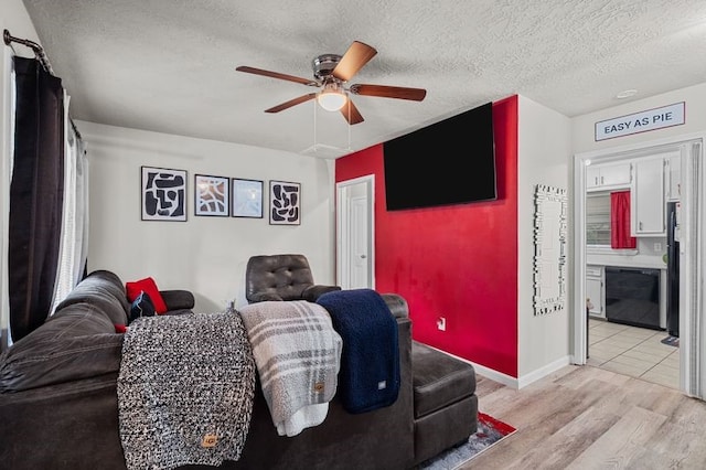 living room with light hardwood / wood-style floors, a textured ceiling, and ceiling fan