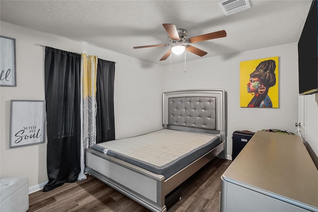 bedroom featuring dark wood-type flooring, ceiling fan, and a textured ceiling