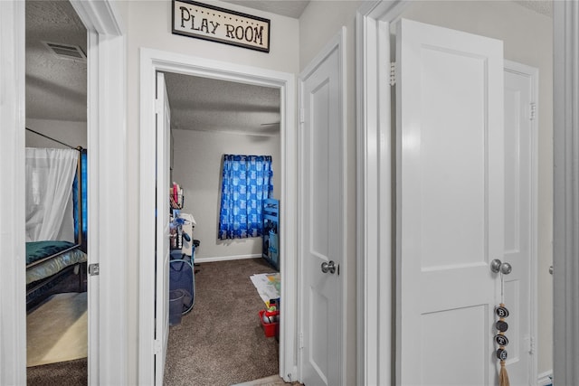 corridor with a textured ceiling and carpet flooring