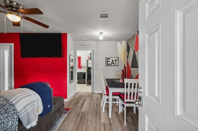 dining space featuring light hardwood / wood-style flooring, a textured ceiling, and ceiling fan