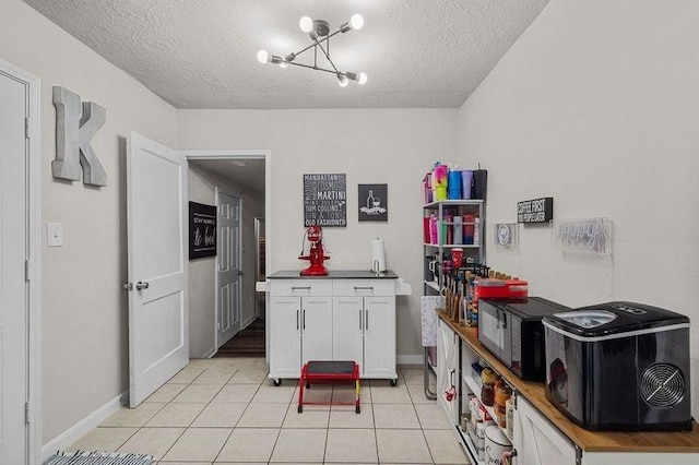 kitchen with white cabinetry, light tile patterned flooring, a textured ceiling, and an inviting chandelier