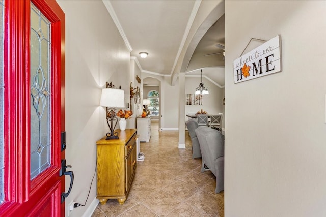 entryway featuring lofted ceiling, ceiling fan with notable chandelier, ornamental molding, light tile patterned floors, and plenty of natural light