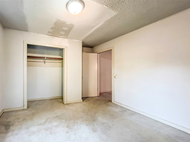 unfurnished bedroom featuring light carpet, a textured ceiling, and a closet