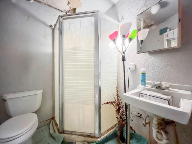 bathroom featuring a shower with door and toilet