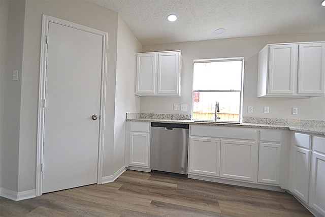 kitchen featuring light wood-type flooring, sink, stainless steel dishwasher, and white cabinets