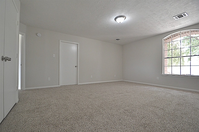 unfurnished room with carpet and a textured ceiling