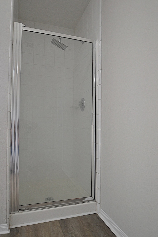 bathroom with a shower with door and hardwood / wood-style floors