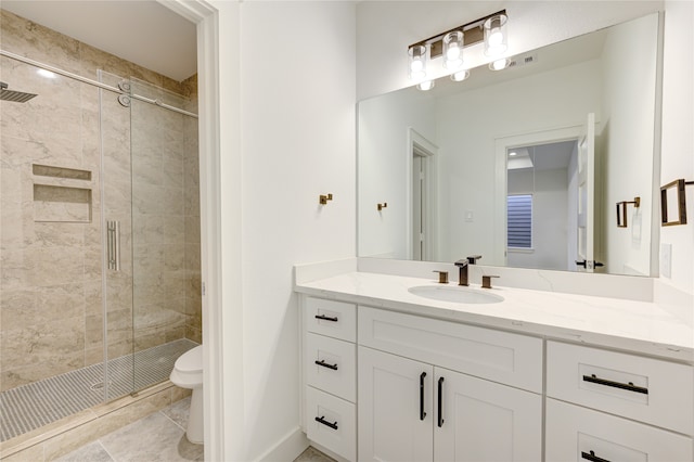 bathroom with tile patterned floors, a shower with door, vanity, and toilet