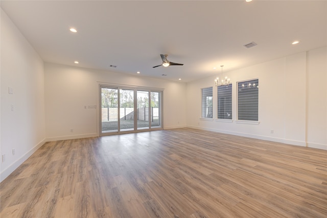 unfurnished room featuring ceiling fan with notable chandelier and light wood-type flooring