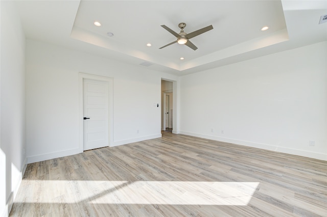 unfurnished bedroom with light hardwood / wood-style floors, a raised ceiling, and ceiling fan