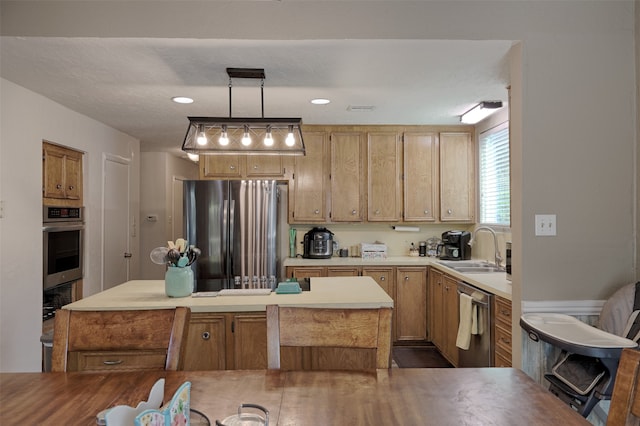 kitchen with appliances with stainless steel finishes, a kitchen island, hanging light fixtures, and sink