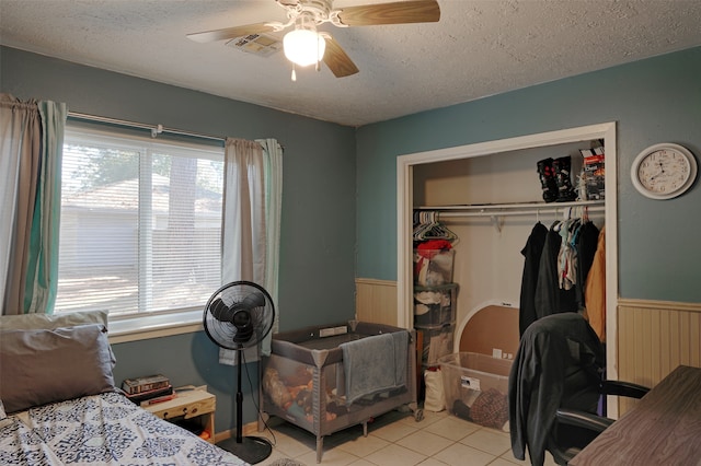 bedroom featuring light tile patterned floors, a textured ceiling, a closet, and ceiling fan