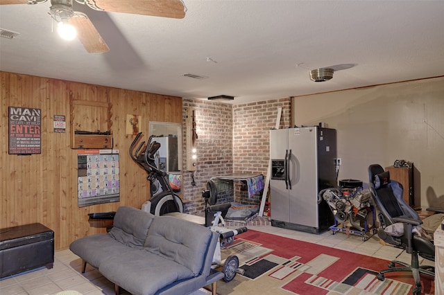 workout room with wood walls, ceiling fan, and a textured ceiling