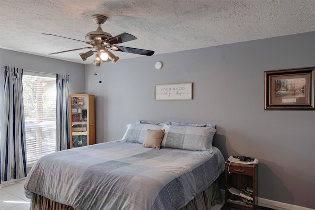 bedroom with ceiling fan, light tile patterned floors, and a textured ceiling