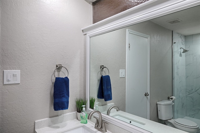 bathroom with vanity, toilet, and a tile shower