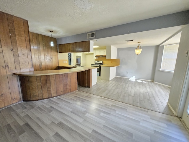 kitchen with hanging light fixtures, light hardwood / wood-style flooring, kitchen peninsula, a textured ceiling, and stainless steel electric stove