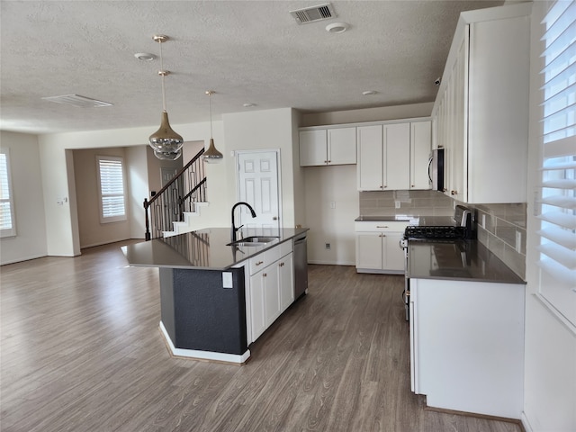 kitchen with an island with sink, wood-type flooring, sink, white cabinetry, and appliances with stainless steel finishes