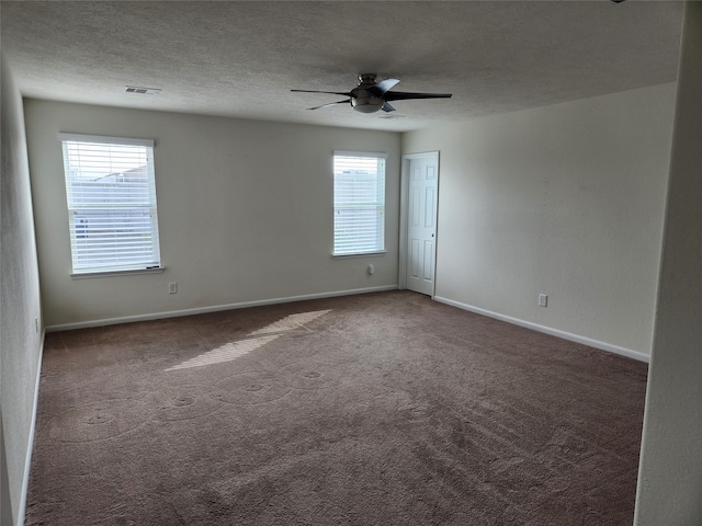 carpeted empty room with a textured ceiling, a healthy amount of sunlight, and ceiling fan