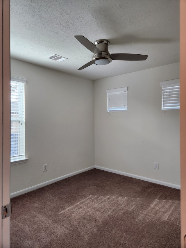 empty room with dark colored carpet, a textured ceiling, and ceiling fan