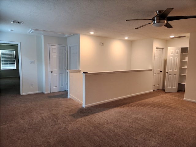 empty room featuring ceiling fan, a textured ceiling, and dark colored carpet